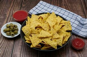 Nachos in a bowl with tomato sauce and olives. Tortilla chips isolated on white background. photo