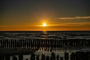 vistoso puesta de sol terminado el polaco báltico mar con oscuro cielo nubes y rompeolas foto