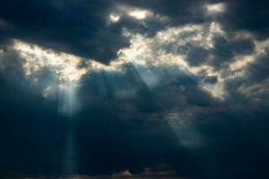 threatening dramatic sky with dark clouds and rays of summer sun photo