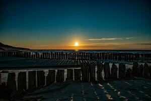 vistoso puesta de sol terminado el polaco báltico mar con oscuro cielo nubes y rompeolas foto