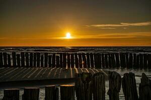 vistoso puesta de sol terminado el polaco báltico mar con oscuro cielo nubes y rompeolas foto