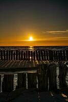 vistoso puesta de sol terminado el polaco báltico mar con oscuro cielo nubes y rompeolas foto