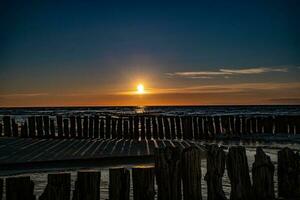 vistoso puesta de sol terminado el polaco báltico mar con oscuro cielo nubes y rompeolas foto