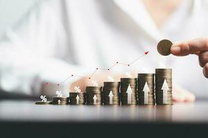 Business woman hand and stack coins money with up arrow and percentage symbol of Interest rate financial and mortgage rates. Icon percentage symbol and arrow pointing up. photo