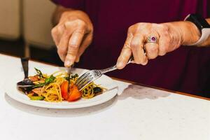 mujer come italiano pasta con tomate utilizando cuchillo y tenedor. foto