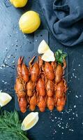 cooked crawfish on platter with lemons and spices on dark background photo
