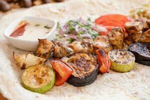 Grilled kebab with pita bread and vegetables on tray in summer fast food street cafe photo