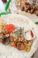 Grilled kebab with pita bread and vegetables on tray in summer fast food street cafe photo