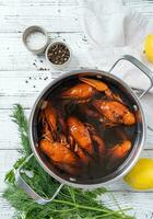 cooked crawfish in saucepan with lemons and spices on wooden background photo