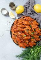 top view of cooked crawfish platter with lemons and spices on cement background photo
