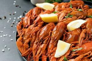 top view of cooked crawfish platter with lemons and spices on cement background photo