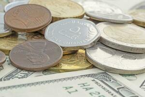 heap of coins lying on one hundred dollars banknotes photo