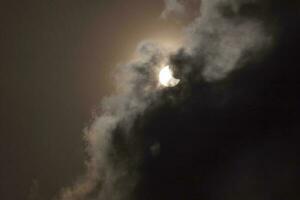 partial eclipse of sun in a cloudy sky photo