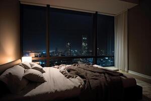 Large bed in living room with night city view in window. photo