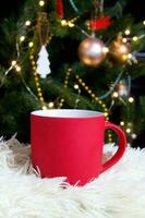 blanco rojo jarra con Navidad árbol en fondo, estera té o café taza con Navidad y nuevo año decoración,horizontal burlarse de arriba con cerámico jarra para caliente bebidas, vacio regalo impresión modelo foto