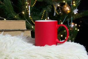 Blank red mug with christmas tree on background,mat tea or coffee cup with christmas and new year decoration,horizontal mock up with ceramic mug for hot drinks,empty gift print template photo