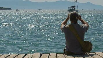 Reisender Mann nehmen Seelandschaft Foto beim funkelnd Meer Strand video