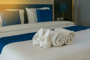 blanco toalla hermosamente arrollado y doblada poner eso en el cama ese el hotel tiene preparado para el invitados quien ven a permanecer. suave y selectivo enfocar. foto