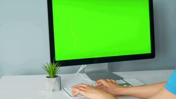 mulher digitando em uma computador teclado às casa escritório, monitor com uma verde tela. croma chave. cópia de espaço. conceito do controlo remoto trabalhar. video