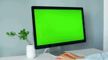 mujer mecanografía en un computadora teclado a hogar oficina, monitor con un verde pantalla. croma llave. Copiar espacio. concepto de remoto trabajar. video