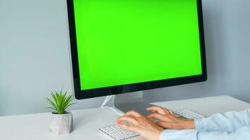 Woman typing on a computer keyboard at home office, monitor with a green screen. Chroma key. Copy Space. Concept of remote work. video