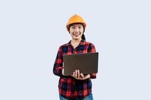 Young female engineer wearing Yellow helmet and use laptop computer photo