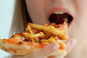 Closeup female mouth bites off a piece of pizza, food. photo