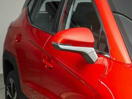 Side mirror of a  red car close up. Exterior detail photo