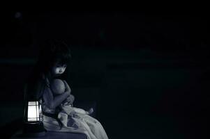 triste niño fantasma a noche de halloween festival concepto, viernes 13, terror película escena,a niña con muñeca foto