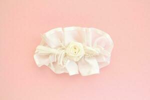 Handmade white wedding hair bow barrette on pink background. Elegant fashion design accessory for woman. Evening hairstyle silk ribbon. Hairpin for girl. Bridal clasp clips with jewellery details photo