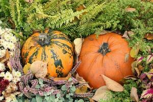 Pumpkins and autumn flowers on a haystacks. Harvest time on a farm. Fall fair of fresh organic vegetables. Festive decor in garden. Agriculture market. Rural scene. Vegetarian and vegan food day. photo