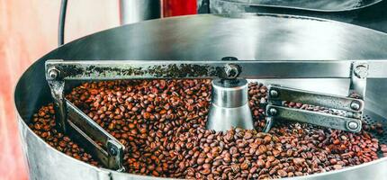 granos de café aromáticos recién tostados sobre una moderna máquina tostadora de café. foto
