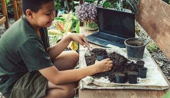 Boy learns to grow flowers in pots through online teaching. shoveling soil into pots to prepare plants for planting leisure activities concept photo