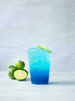 Blue Hawaiian drink in a plastic glass and lime on white background photo