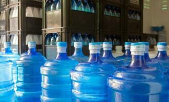 el galón de agua azul que contiene agua potable ha sido sellado con un sello de plástico en la planta de agua potable para esperar la entrega foto