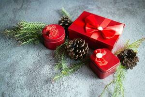 Christmas decoration composition on gray concrete background with a beautiful Red gift box with red ribbon, tree branches, and pine cones photo