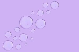 grande redondo soltar de transparente cosmético gel en un púrpura antecedentes. foto