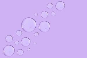 Large round drop of transparent cosmetic gel on a purple background. photo