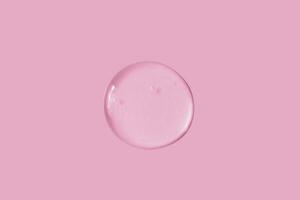 texture of a large smear of transparent gel on a pink background photo