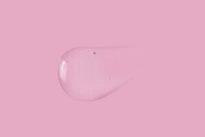 texture of a large smear of transparent gel on a pink background photo