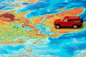 pequeño rojo juguete coche en el físico mapa de el mundo en África, viaje contenido foto