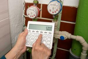 hands with a calculator at water meters, utility bills photo