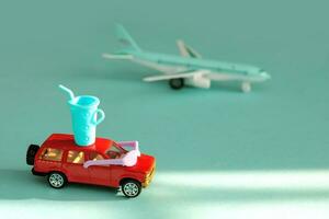 toy car in sunglasses, with a glass of cocktail on the roof on the background of a flying plane, vacation content photo