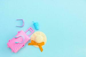 toy pink suitcase, sunglasses, straw hat and glass with cocktail on blue background with copy space, vacation content photo