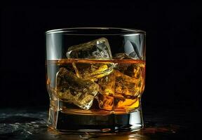 Whiskey with ice in glass on black background photo