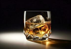 Whiskey with ice in glass on black background photo