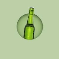 Green bottle of fresh beer with drops of condensation on pastel green background photo