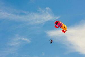 Parachutists fly in the blue sky with a colorful parachute photo