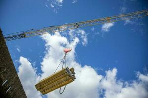 Low angle view of crane carrying construction materials to a construction site. photo