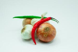 Group of fresh garlic, onions, red and green chilis on white background photo